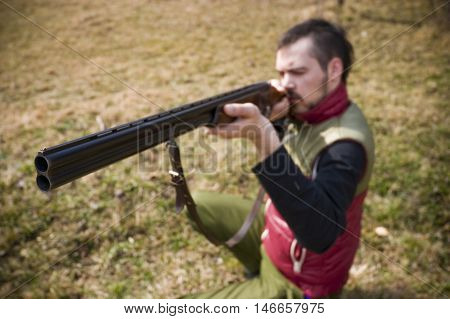Hunter preparing to shoot rifle aiming in a garden