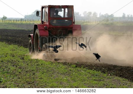 Farmer working the field with tractor in rural landscape.