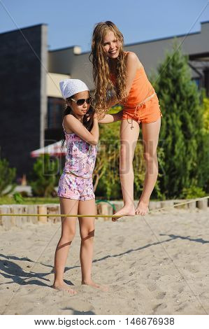 Two girls having fun on sling. Girl teenagers learn to walk on a tightrope with his girlfriend.