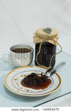 Jam made from pine cones on a plate and a cup of tea