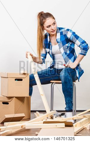 Woman Moving Into Apartment Assembly Furniture.