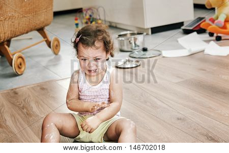 Naughty little child sitting on the floor