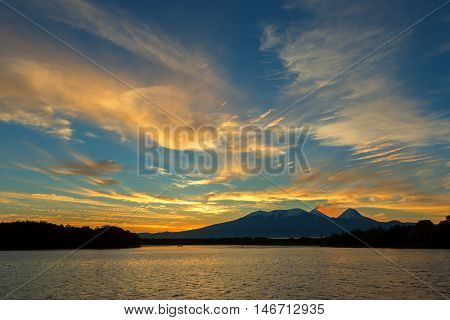 Beautiful sunrise over the volcanoes Kluchevskaya group with reflection in the river Kamchatka.