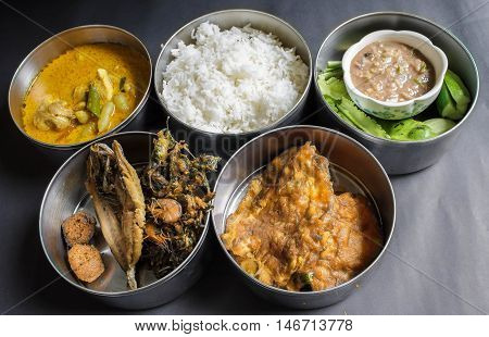 Thai food in food carrier Thai style,fried fish,chicken curry ,chili shrimp paste sauce,vegetable,stream rice,Thai Omelette,Curried shrimp fried