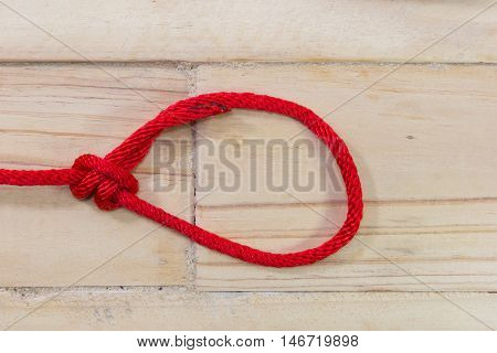 bowline knot made from red synthetic rope tightening on wooden background.