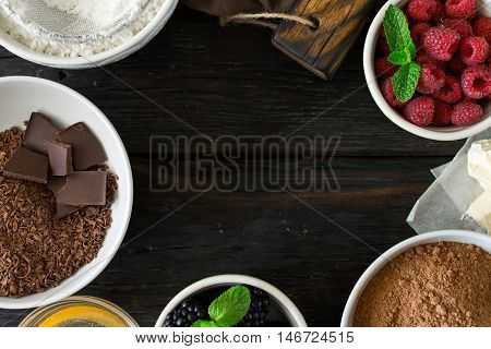 Frame of food ingredients for cooking chocolate dessert on dark wooden background top view