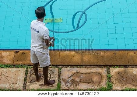 The attendant cleans the pool bottom with a special vacuum cleaner.