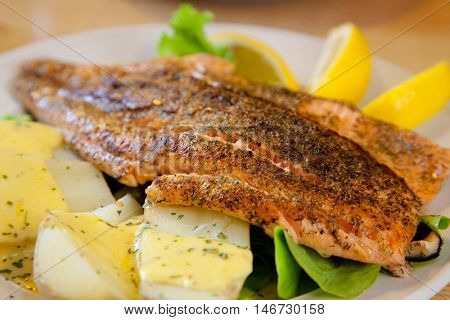 gourmet Grilled Salmon Steak with baked potato and lemon meal (selective focus at front)