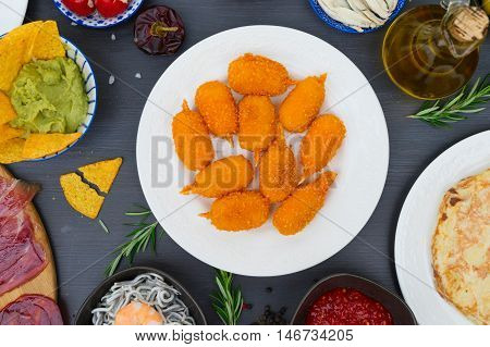 Table with spanish tapas - jamon, croquetes, guacamole and olives, top view, picnic table