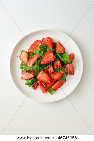 Spinach and strawberry salad with poppy seeds and vegetable oil dressing healthy and refreshing vegetarian dish top view
