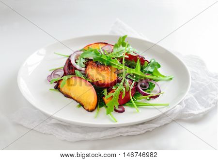 Vegetarian gourme salad made of grilled peaches slices red onion and arugula