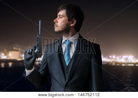 Agent Or Hitman Holds Pistol With Silencer In Hand At Night.