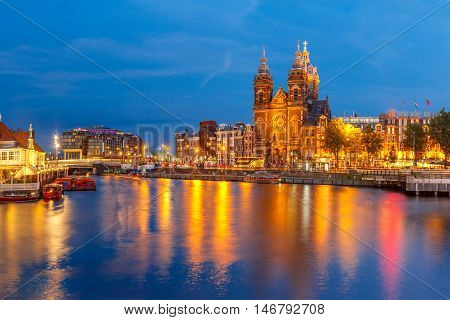 Night panoramic city view of Amsterdam canal, bridge and Basilica of Saint Nicholas, Holland, Netherlands. Long exposure.