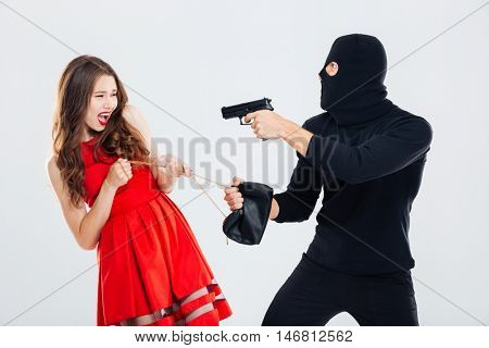 Man theif in balaclava threatening with gun and stealing young woman bag