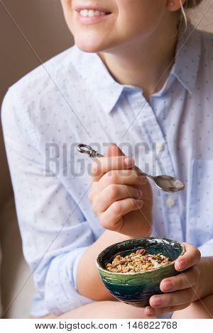 Young woman with muesli bowl. Girl eating breakfast cereals with nuts pumpkin seeds oats and yogurt in bowl. Girl holding homemade granola. Healthy snack or breakfst in the morning.