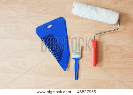 Working tools for repair and construction isolated on wooden texture background paint roller, brush and spatula. House decorating and improvement concept. Top view copy space