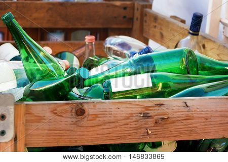 green empty glass wine glass bottels on a heap in wooden box