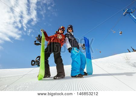 Friends snowboarders stands on the slope of mountain with snowboards