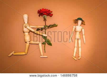 Red rose and figure wooden man and woman on brown background