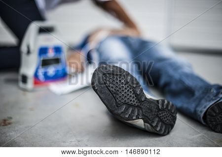 girl assisting an unconscious man with defibrillator