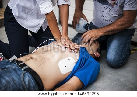people making CPR with defibrillator to an unconscious man