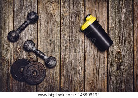 Old iron dumbbells or exercise weights with extra plates on an old wooden deck, floor or table. Image taken from above, top view. A lot of copy space around product