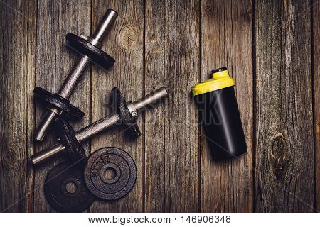 Old iron dumbbells or exercise weights with extra plates on an old wooden deck, floor or table. Image taken from above, top view. A lot of copy space around product