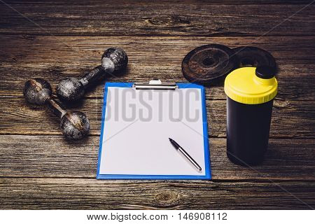 Old iron dumbbells or exercise weights with extra plates on an old wooden deck, floor or table. Image taken from above, low angle . A lot of copy space around product