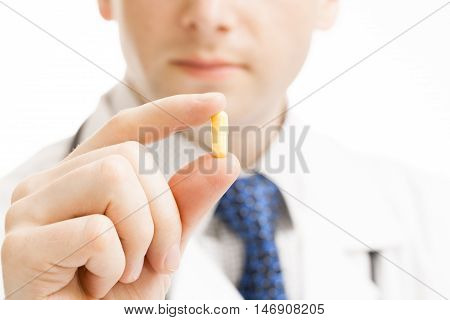 Male doctor holdling pill in hand - studio shot
