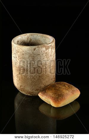 Cup of wine and bread as symbols of Communion over dark background