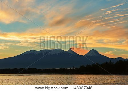 Beautiful sunrise over the volcanoes Kluchevskaya group with reflection in the river Kamchatka.