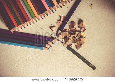 Colored pencils angle / Many different colored pencils on cement background / sharpened pencil with shavings
