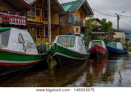 PASTO, COLOMBIA - JULY 3, 2016: some colorfull boats parked next to a shore and some houses in la cocha lake.