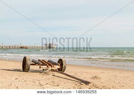 wooden boat trailer for transportation on beach near fishing jetty .