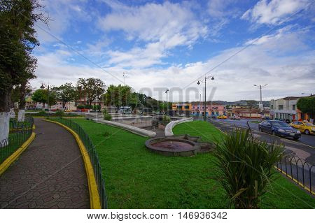 TULCAN, ECUADOR - JULY 3, 2016: some autos driving on the street next to an empty park.