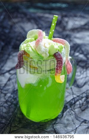 Green drink with ice cream float and gummy worms for Halloween