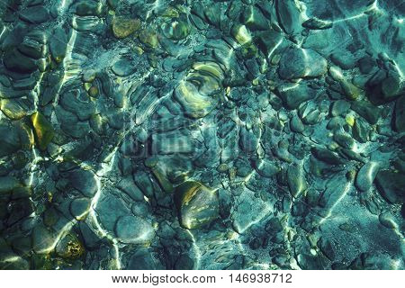 Sparkling with gild pebbles under clear aquamarine water