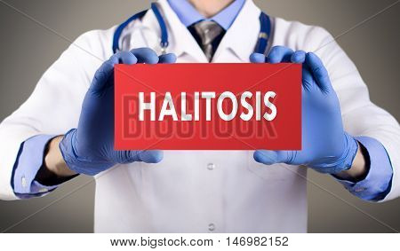 Doctor's hands in blue gloves shows the word halitosis. Medical concept.