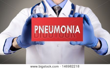 Doctor's hands in blue gloves shows the word pneumonia. Medical concept.