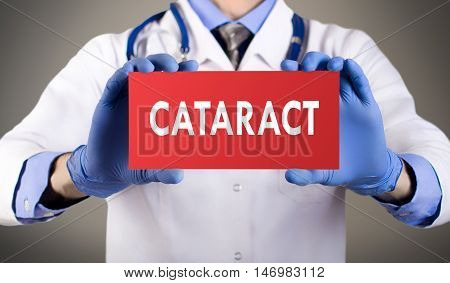 Doctor's hands in blue gloves shows the word cataract. Medical concept.