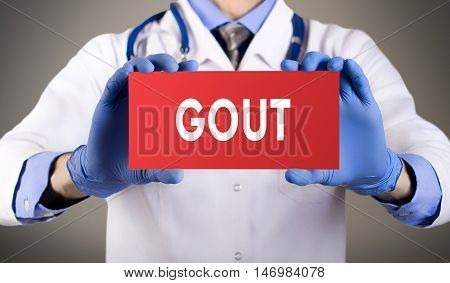 Doctor's hands in blue gloves shows the word gout. Medical concept.