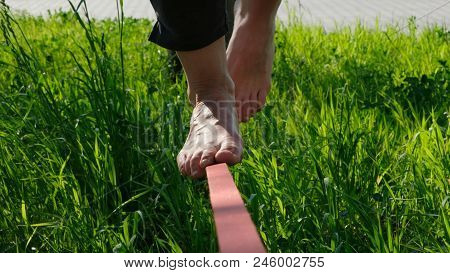 Woman Legs Walk Along A Tight Line In A City Park. Girl Of The Foot Balances On Slakcline, Goes Back