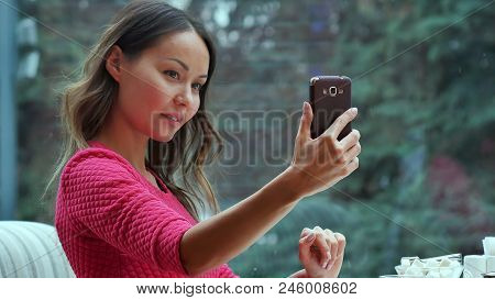 Attractive Woman Taking Self Portrait By Mobile Phone In Cafe