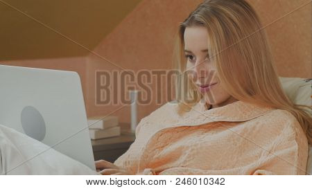 Full Length Side View Of Female Patient Using Laptop On
