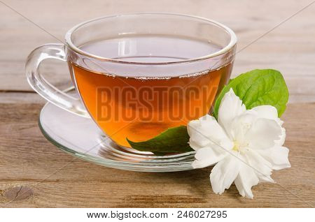 Glass Cup Of Tea With Jasmine Flowers On Wooden Table