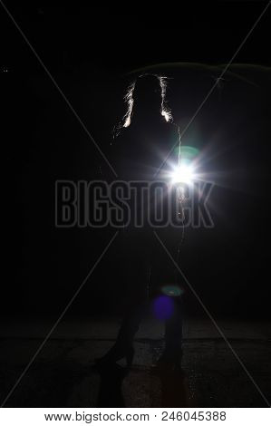Silhouette Of A Woman At Night And The Light Outline Around Her. Black Background