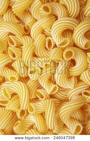 Ellow Background Of Pasta In The Form Of Tubes Spun In A Spiral