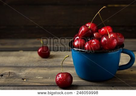 Fresh Cherry With Beautiful Drops In A Blue Enamel Mug