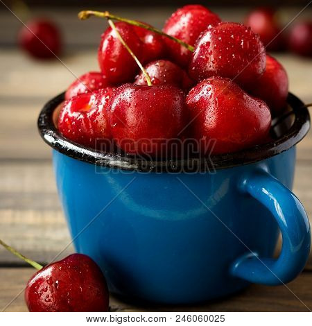 Fresh Cherry With Beautiful Drops In A Blue Enamel Mug