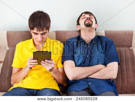 Sleepy Man And A Guy With A Tablet Computer On The Sofa